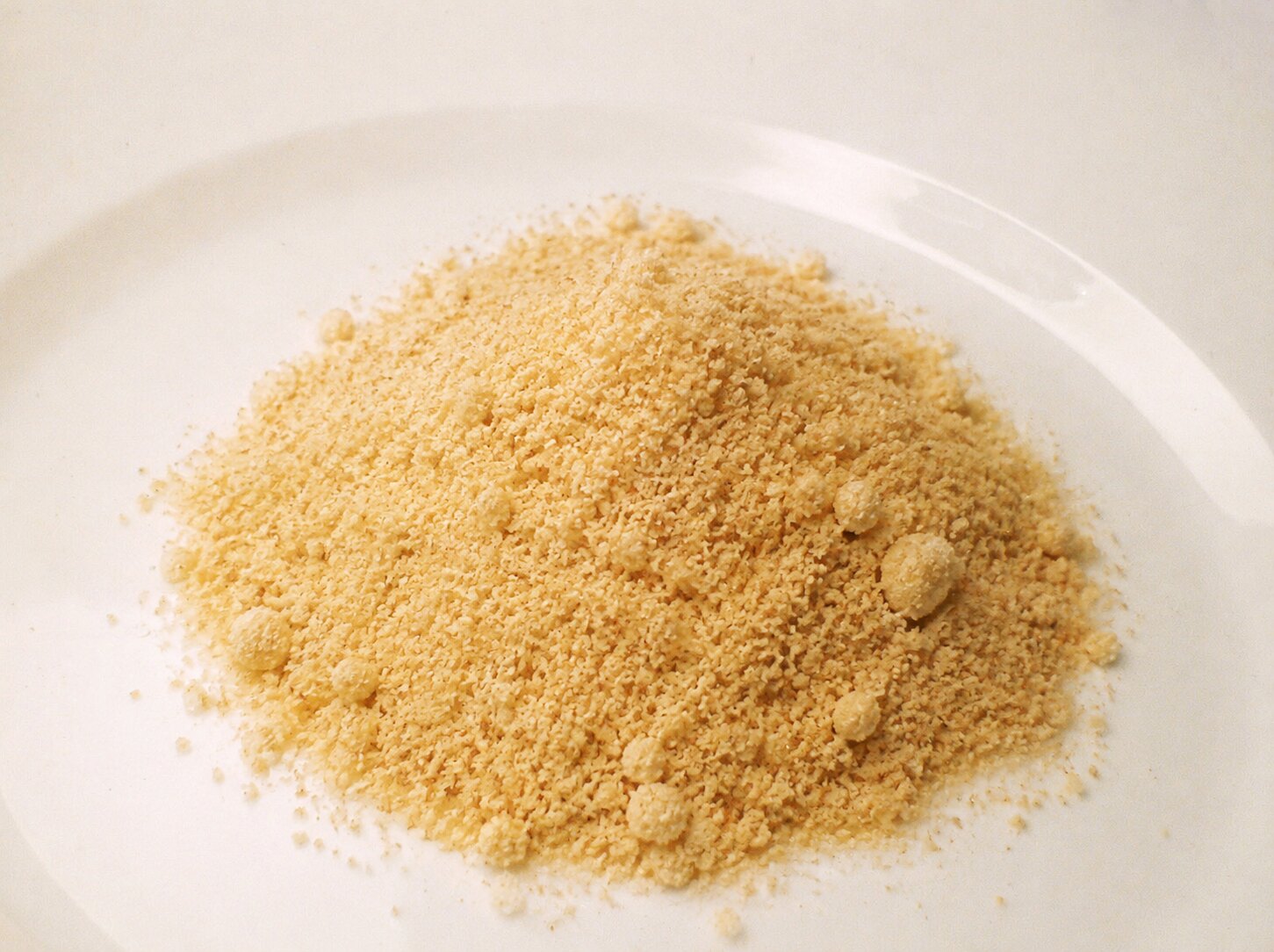 Natural golden powdered Cambodian palm sugar on a plain white plate
