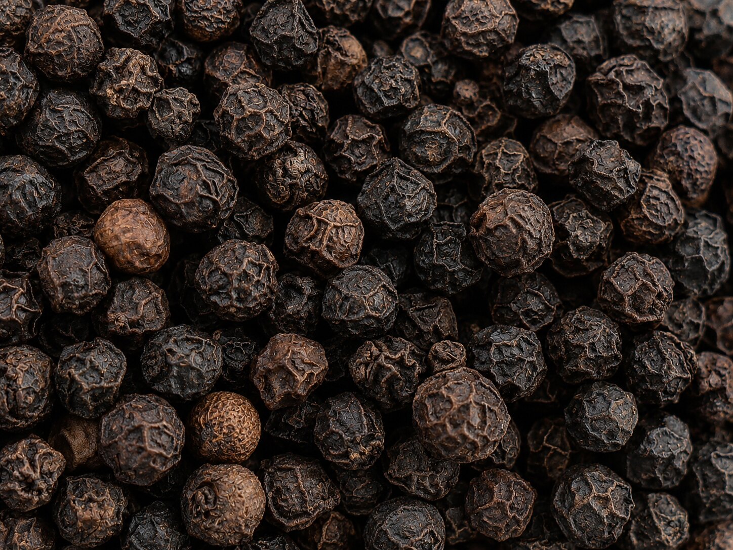 Clean premium whole black peppercorns in a natural close-up